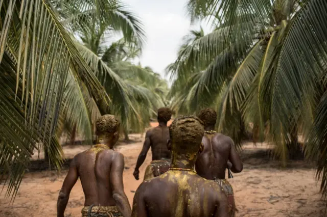 Voodoo devotees walk through a palm tree plantation on their way to the annual Voodoo Festival on January 10, 2017 in Ouidah.