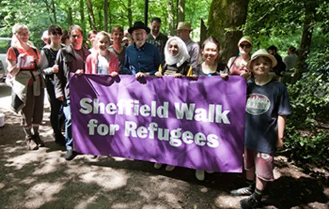 Sir Keith on Sheffield walk for refugees holding banner