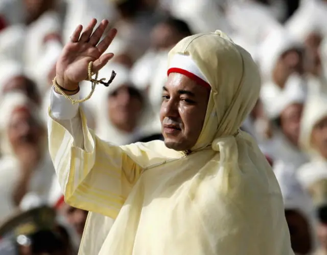 King Mohammed VI of Morocco waves to crowds of men dressed in traditional white robes during Throne Day Celebrations at the Royal Palace on July 31, 2006 in Rabat, Morocco