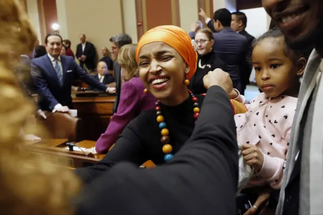 Ilhan Omar greeting others after her swearing in ceremony.