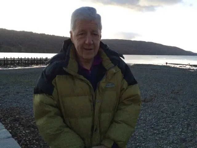 Anthony Robinson standing beside Coniston Water