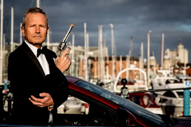 Peter Levy poses as Bond by the marina