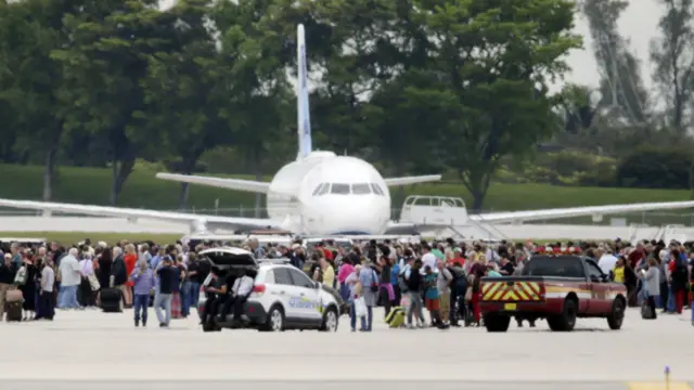 People stand on the tarmac at the Fort Lauderdale-Hollywood International Airport