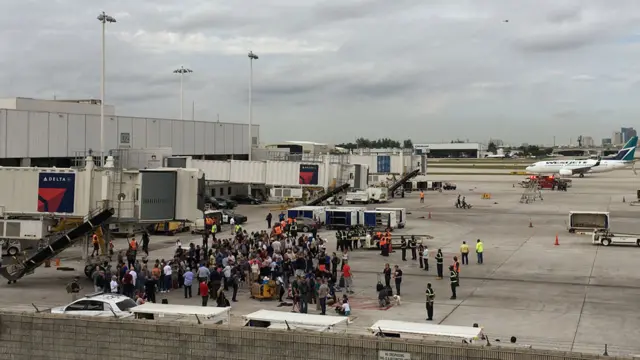 People stand on the tarmac at the Fort Lauderdale-Hollywood International Airport