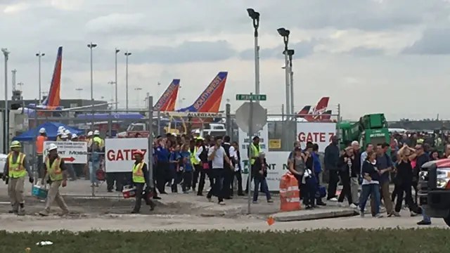 People stand on the tarmac at the Fort Lauderdale-Hollywood International Airport