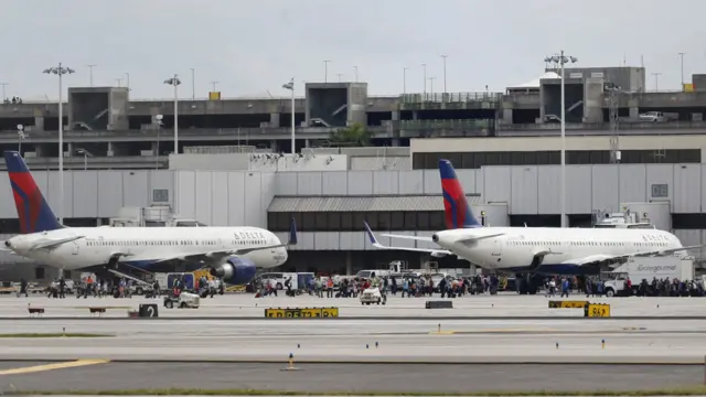 People stand on the tarmac at the Fort Lauderdale-Hollywood International Airport