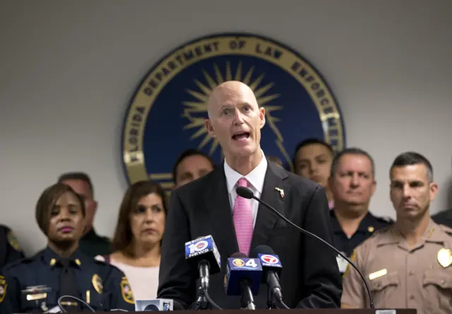 Joined by law enforcement officials, Fla. Gov. Rick Scott, center, speaks during a news conference at the Florida Department of Law Enforcement (FDLE) Miami Regional Operations Center, Thursday, Jan. 5, 2017, in Miami.