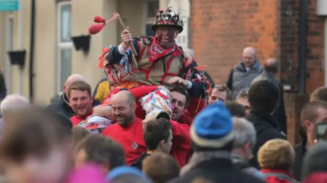 The Haxey fool is carried through the village to start the Haxey Hood Game