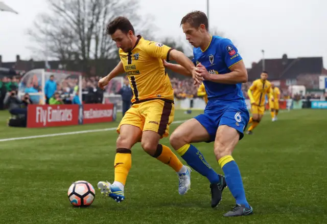 Matt Tubbs of Sutton United controls the ball under pressure of Will Nightingale of AFC Wimbledon