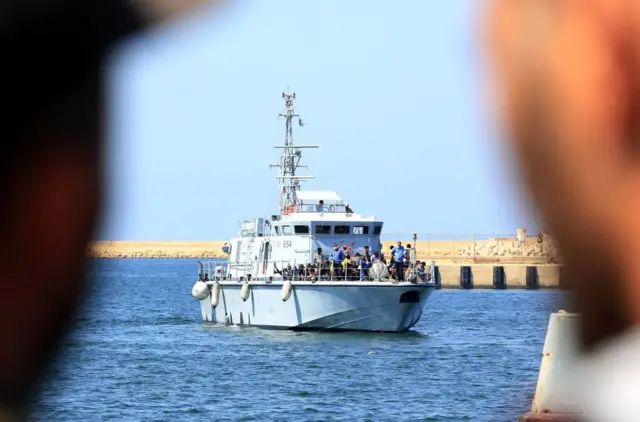 Illegal migrants from Africa sit on a Libyan coastguard boat as they arrive at a naval base in Tripoli after being rescued in the Mediterranean Sea, off the Libyan coast, on August 28, 2017