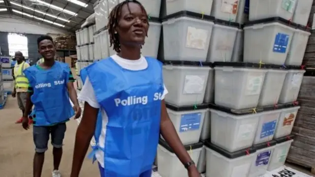 Staff at a polling stations seen next to ballot boxes