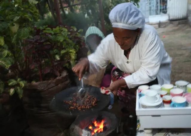A woman roasts coffee beans to prepare traditional coffee for a visitor on March 19, 2013 in Addis Ababa, Ethiopia