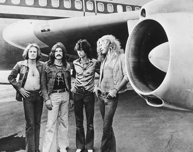 Led Zeppelin, (left - right): John Paul Jones, John Bonham (1948 - 1980), Jimmy Page and Robert Plant, pose in front of an airplane, 1970s