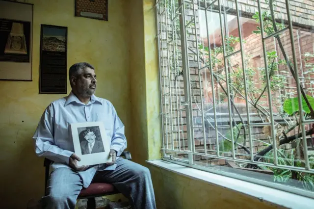 Imtiaz Cajee, the nephew of Ahmed Timol, an anti-apartheid activist brutally murdered in police custody in October 1971, holds a portrait of his uncle at his house on May 25, 2017 in Pretoria