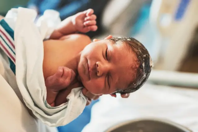 A newborn baby boy has his hair washed