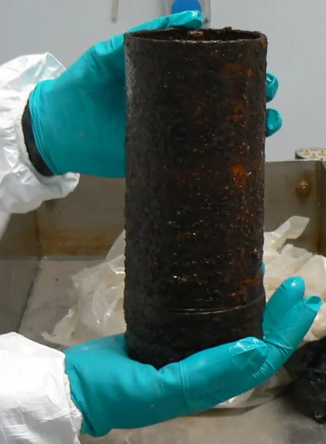 A gloved hand holds a rusty canister