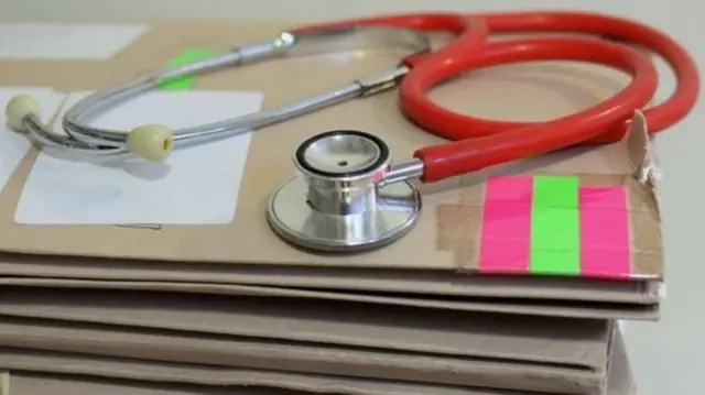 A stethoscope rests atop a stack of folders