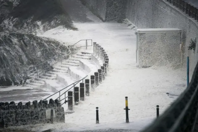 Sea foam covers the promenade at Trearddur Bay