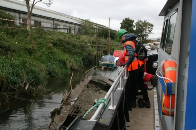 People looking at a sunken boat