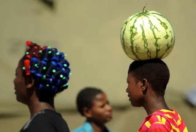 A Zimbabwean mother carries a melon on her head on her way home in Mbare township on March 17, 2013