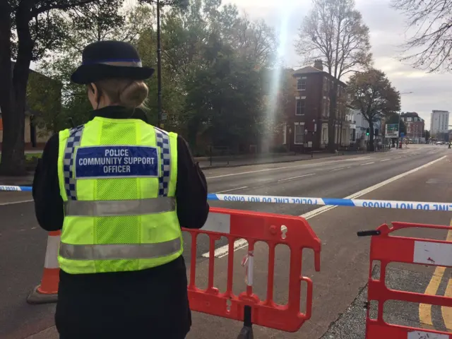 Police community support officer by police cordon