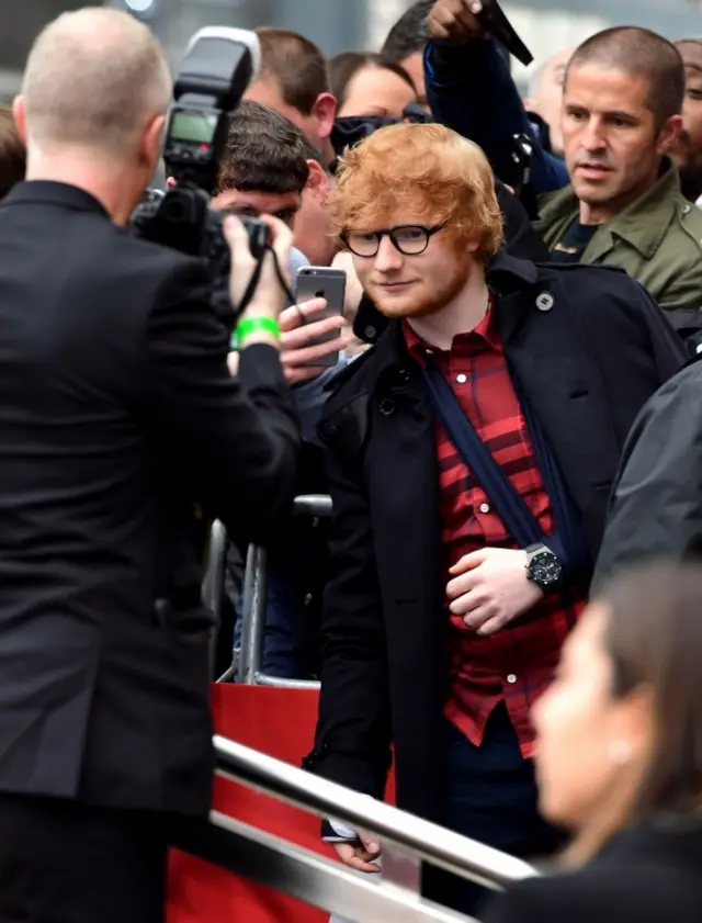 Ed Sheeran, with arm in a sling and cast, poses for photos