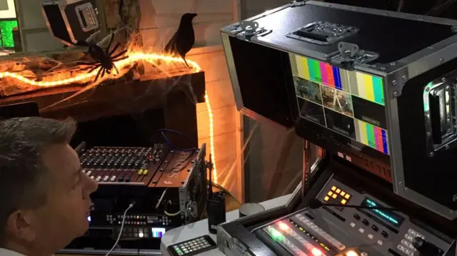 Man looking at monitors surrounded by Halloween decorations