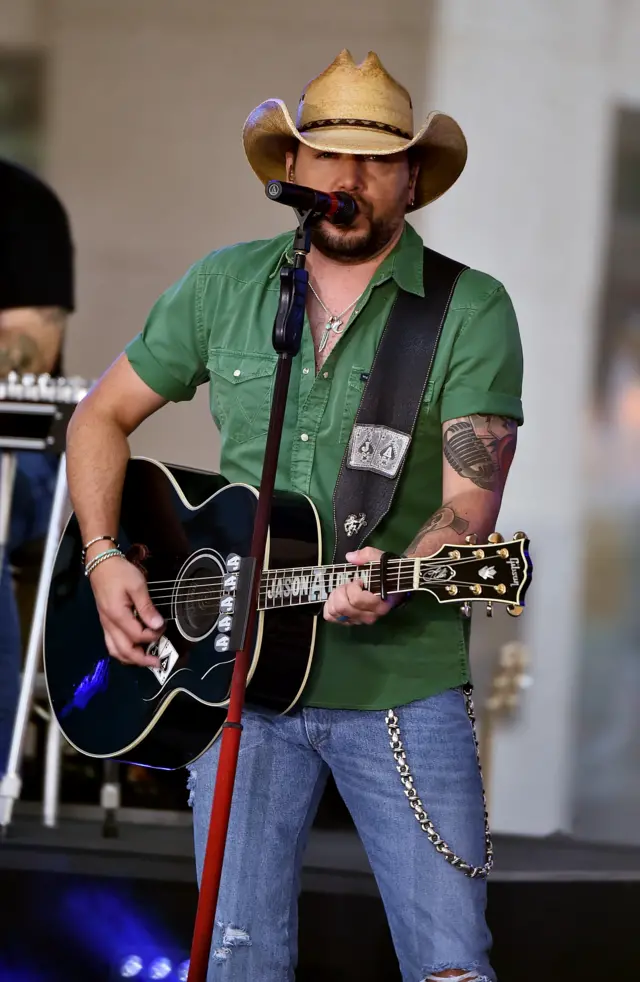 Jason Aldean on stage with guitar, microphone and cowboy hat