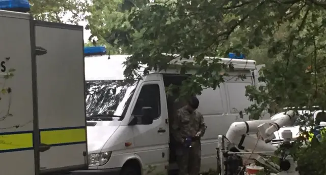 A police bomb disposal officer stands beside a robot