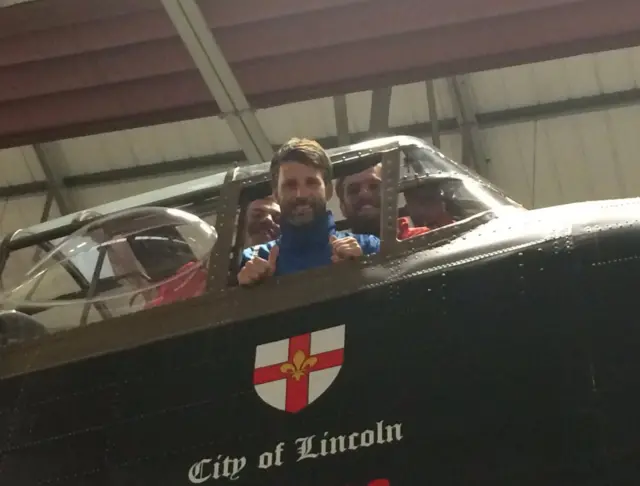 Danny Cowley, Josh Vickers and Harry Anderson poke their heads through the window of the City of Lincoln Lancaster Bomber