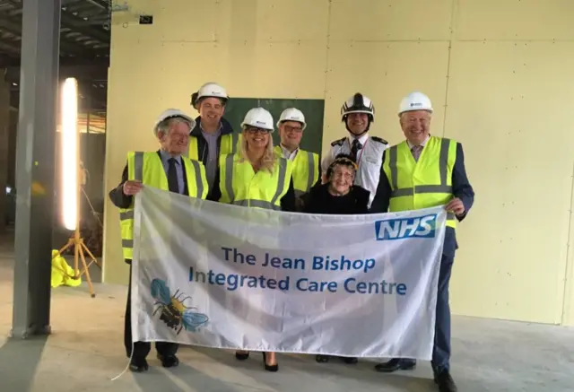 Council officials with Jean Bishop holding a sign saying 'The Jean Bishop Integrated Care Centre'.