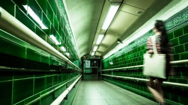 A woman walks down a tube tunnel