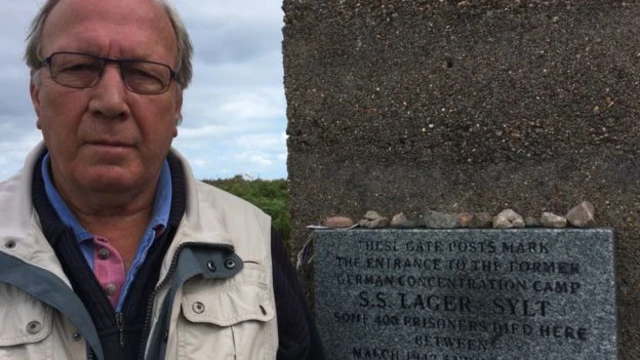 Graham McKinley standing next to the memorial plaque at Lager Sylt