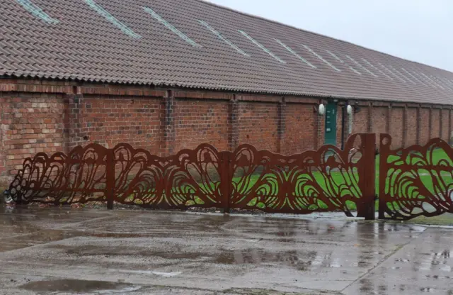 The rusty ornate railings and wet pavement outside the Rope Walk in Barton on Humber.