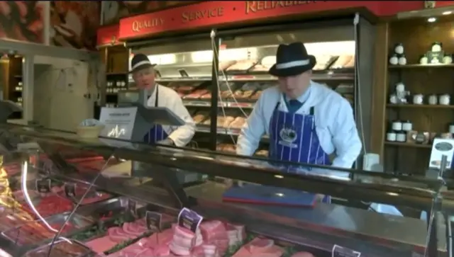 Two butchers stood behind the counter.