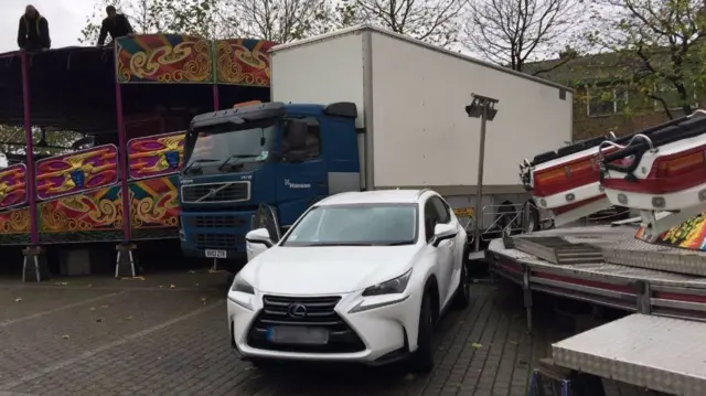 Car with fairground around it