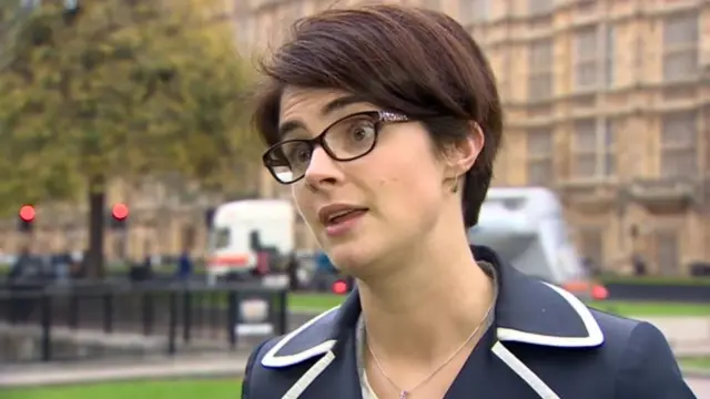 Chloe Smith MP, in blue jacket, stands near Westminster