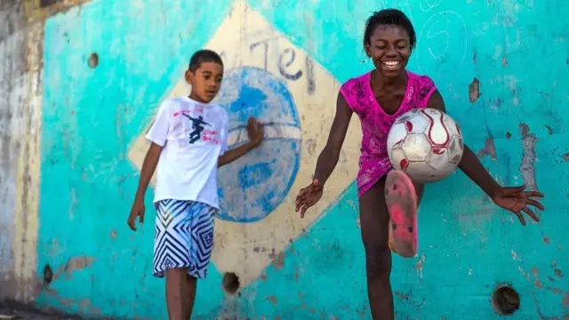 A boy and girl play football in the Chacara do Ceu favela