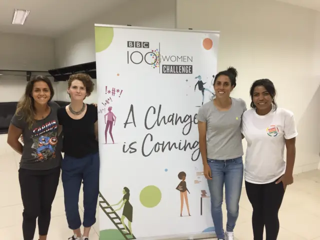 Four women from TeamPlay pictured in front of a 100 Women banner