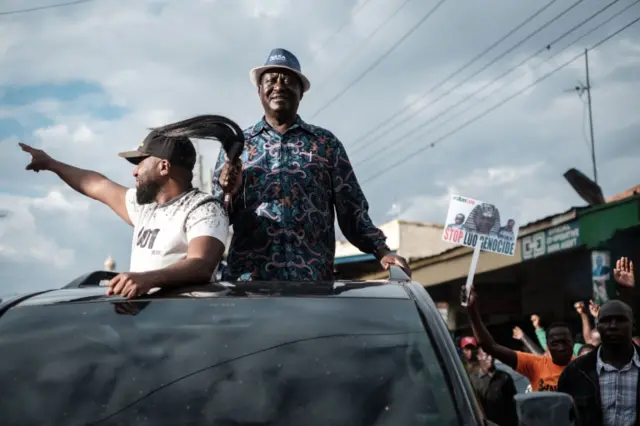 Raila Odinga of the opposition National Super Alliance (NASA) coalition, flanked by Mombasa Governor Hassan Joho (L), gestures to supporters as he stands on a car during a political rally in Machakos, 60 km east of Nairobi on October 24, 2017.