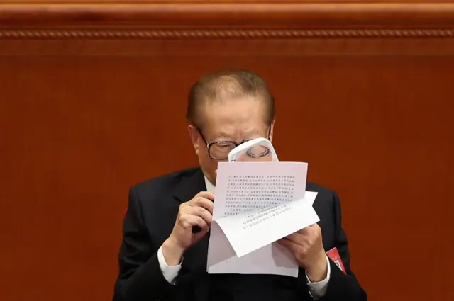 hina"s former president Jiang Zemin reads the file with a magnifying glass during the closing of the 19th Communist Party Congress at the Great Hall of the People on October 24, 2017 in Beijing, China.