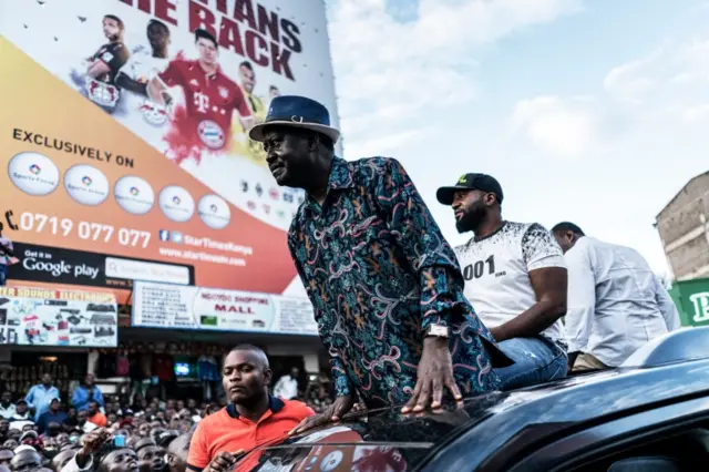 Raila Odinga of the opposition National Super Alliance (NASA) coalition, flanked by Mombasa Governor Hassan Joho (R), stands on a car as he arrives to a political rally in Machakos, 60 km east of Nairobi on October 24, 2017.