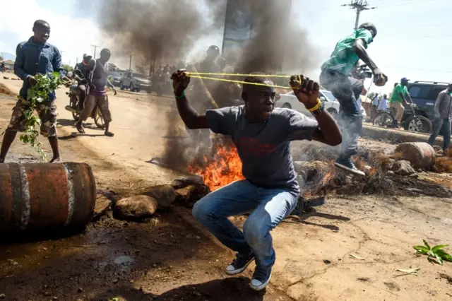 Supporters of National Super Alliance (Nasa) presidential candidate Raila Odinga throw rocks next to burning tyres blocking the road, during a demonstration on the boycott of the upcoming elections on 25 October 2017 in Kisumu, Kenya