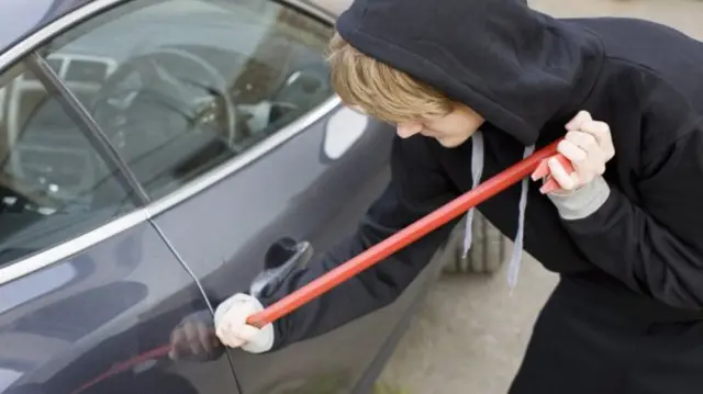 Car thief breaking into car