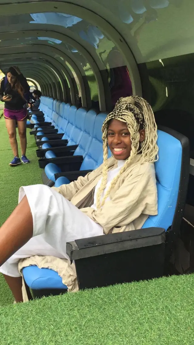 MC Soffia sits on the side of the stadium field and smiles