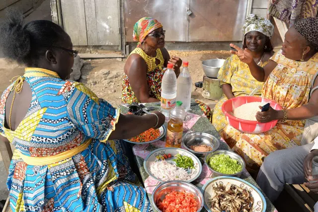 Women share food from a 'pot in a bag', a clever new fad to stew up a tasty rice and tomatoes, that could help fight climate change, on May 31, 2016 in Douala, Cameroon.