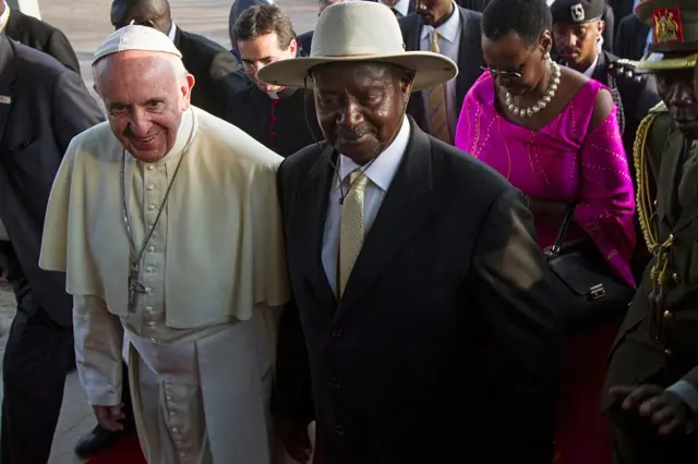 Pope Francis (L) meets with Uganda's President Yoweri Museveni (C) upon his arrival on November 27, 2015 in Entebbe. Pope Francis arrived in Uganda on November 27 on the second leg of a landmark trip to Africa which has seen him railing against corruption and poverty, with huge crowds celebrating his arrival.