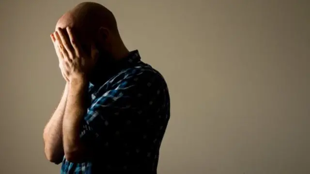 A man holds his head in his hands