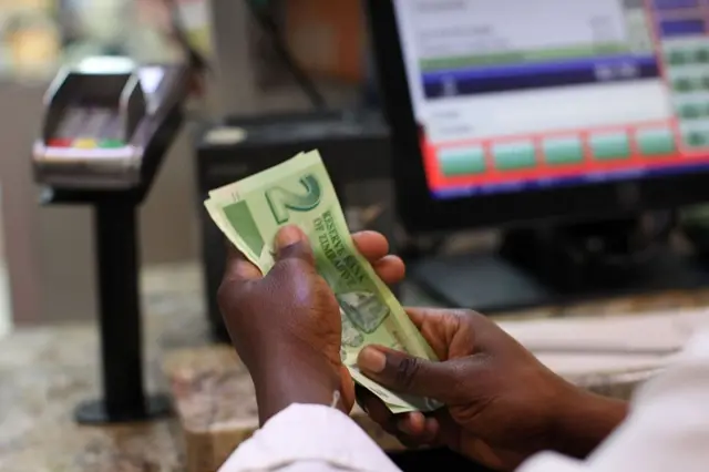 A man holds Zimbabwean bond notes at a till