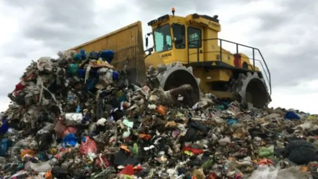 Digger on pile of landfill rubbish